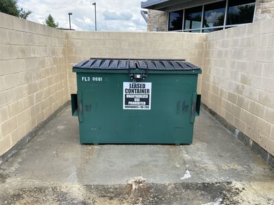Finished dumpster enclosure with clean concrete after commercial pressure washing